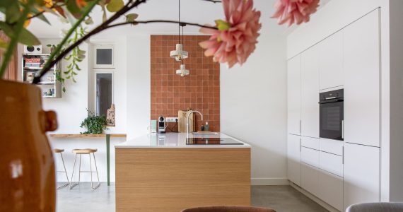 Modern vintage interieur gecombineerd met oranje tegels, een witte keuken en een grijze naadloze vloer van Willem Designvloeren.