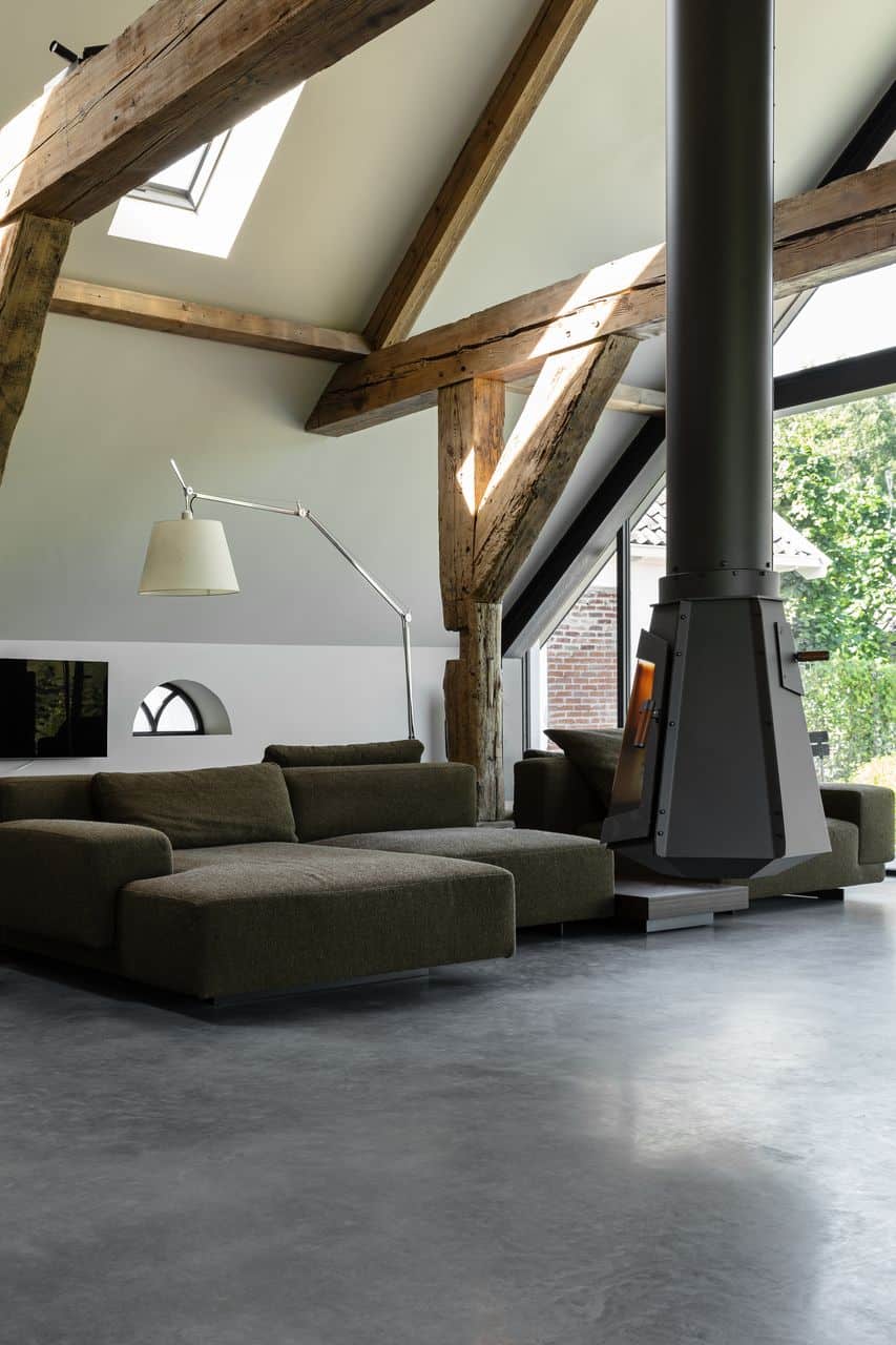 Woonkamer met een grijze bank, een hangende open haard en een gevlinderde betonvloer in Nieuwer ter Aa