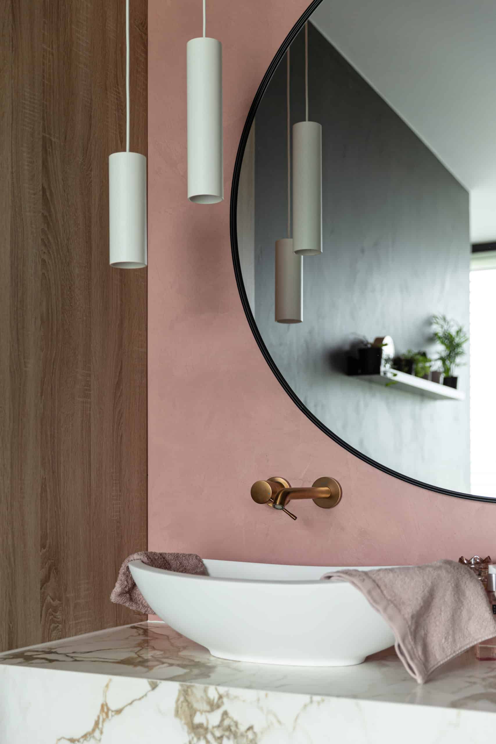 Beton ciré muur in een roze kleur in de badkamer, gecombineerd met een marmeren wastafelblad;