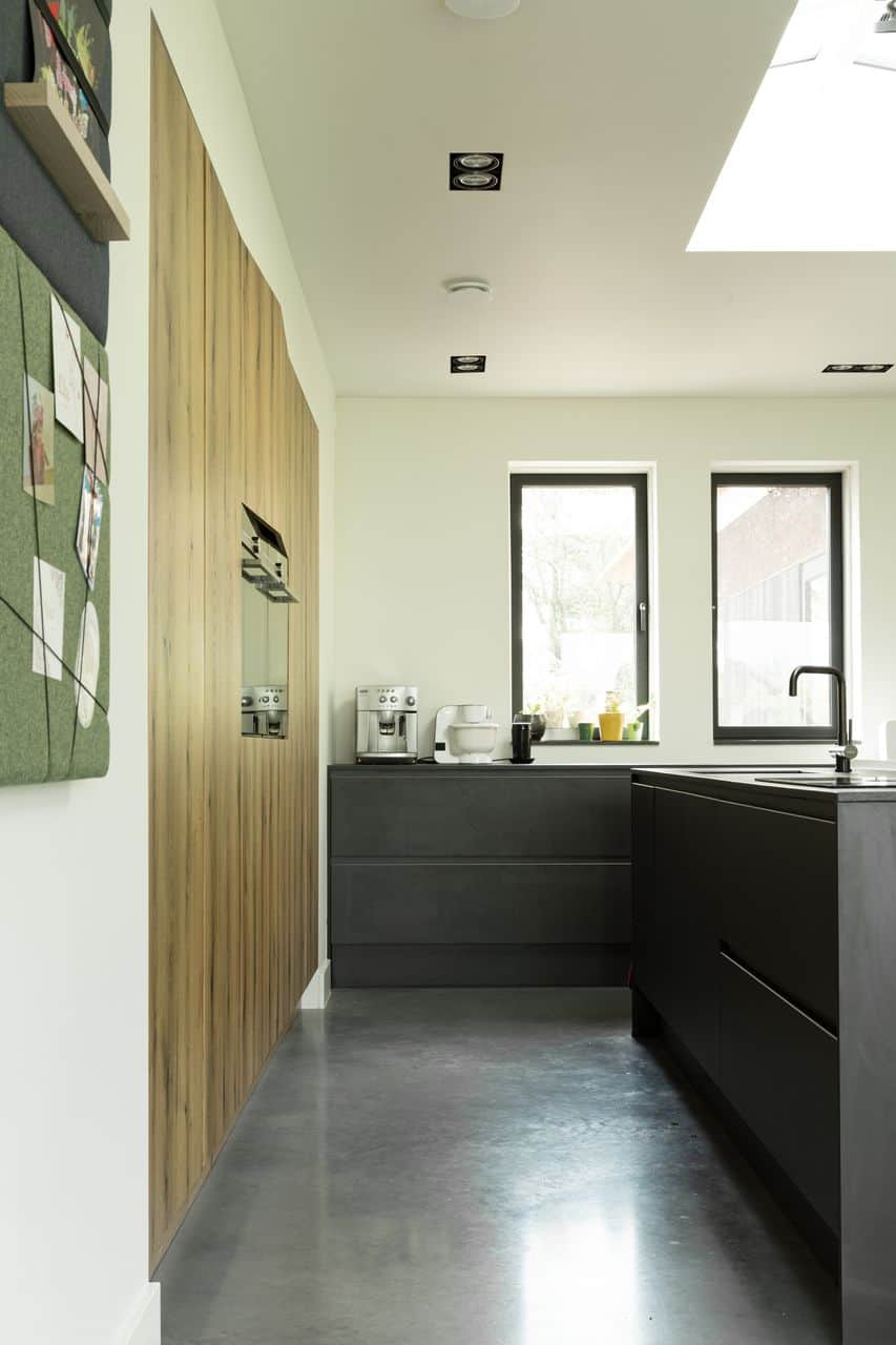 Zwarte keuken met keukeneiland in Eck en Wiel met een gevlinderde woonbeton vloer van Willem Designvloeren