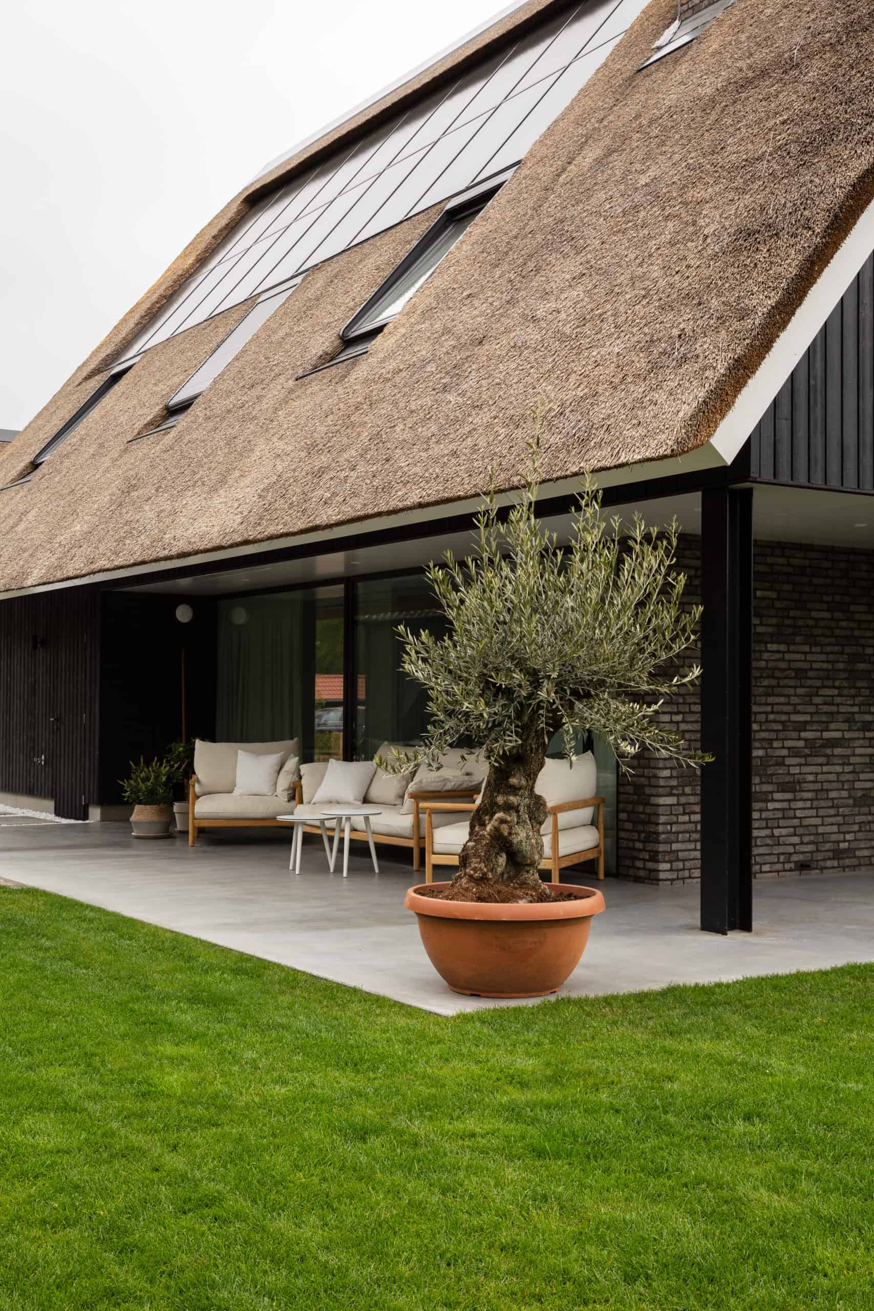 Een gevlinderd betonnen terras bij een vrijstaande woning in Harderwijk. Gecombineerd met een houten tuinset