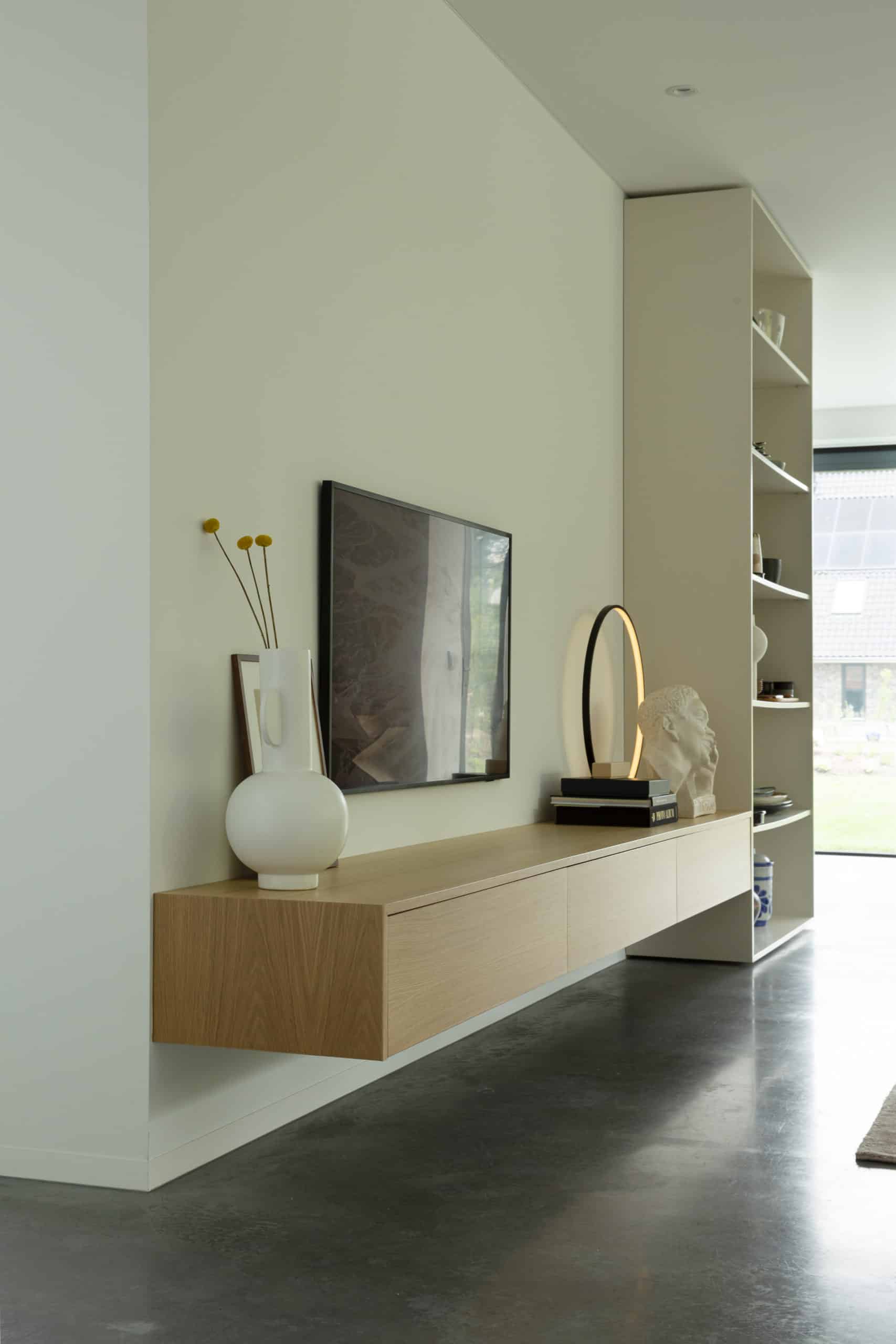 Gevlinderde betonvloer in de woonkamer in Harderwijk. Gecombineerd met een houten tv meubel en witte accesoires