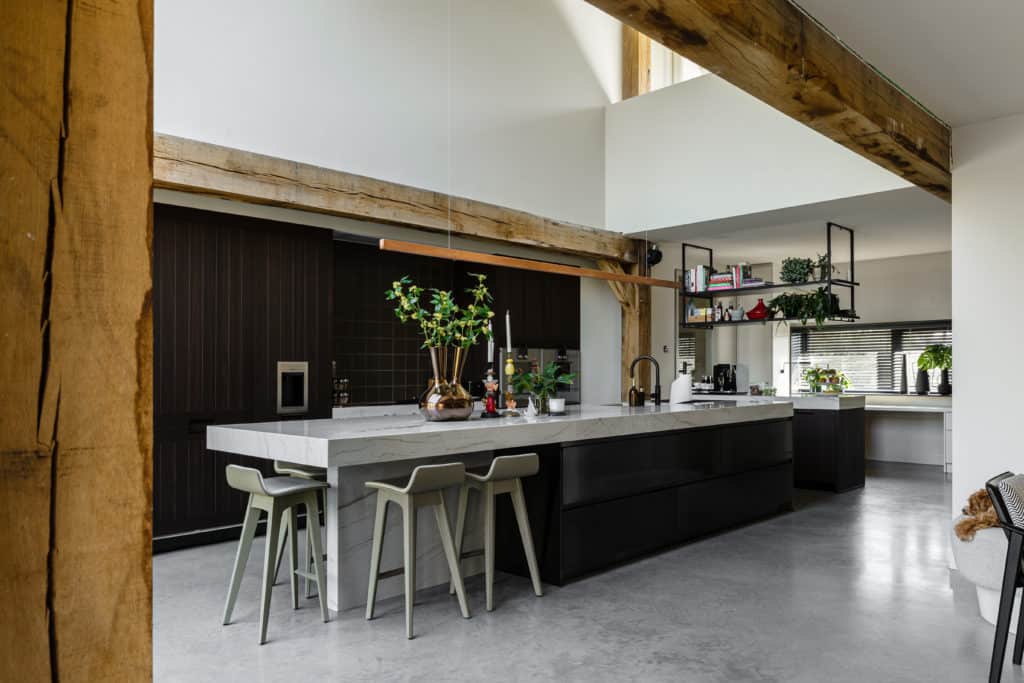 Keukeneiland met een marmeren blad en bruine onderkant gecombineerd met een gevlinderde betonvloer in Oss, designvloeren