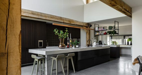 Keukeneiland met een marmeren blad en bruine onderkant gecombineerd met een gevlinderde betonvloer in Oss