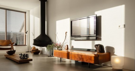 Italiaanse betonlook vloer in de woonkamer in Oostzaan gecombineerd met houten meubels en een zwarte haard.