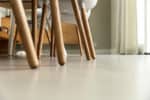 Italiaanse betonlook vloer in Soesterberg met daarop stoelen met houten poten.