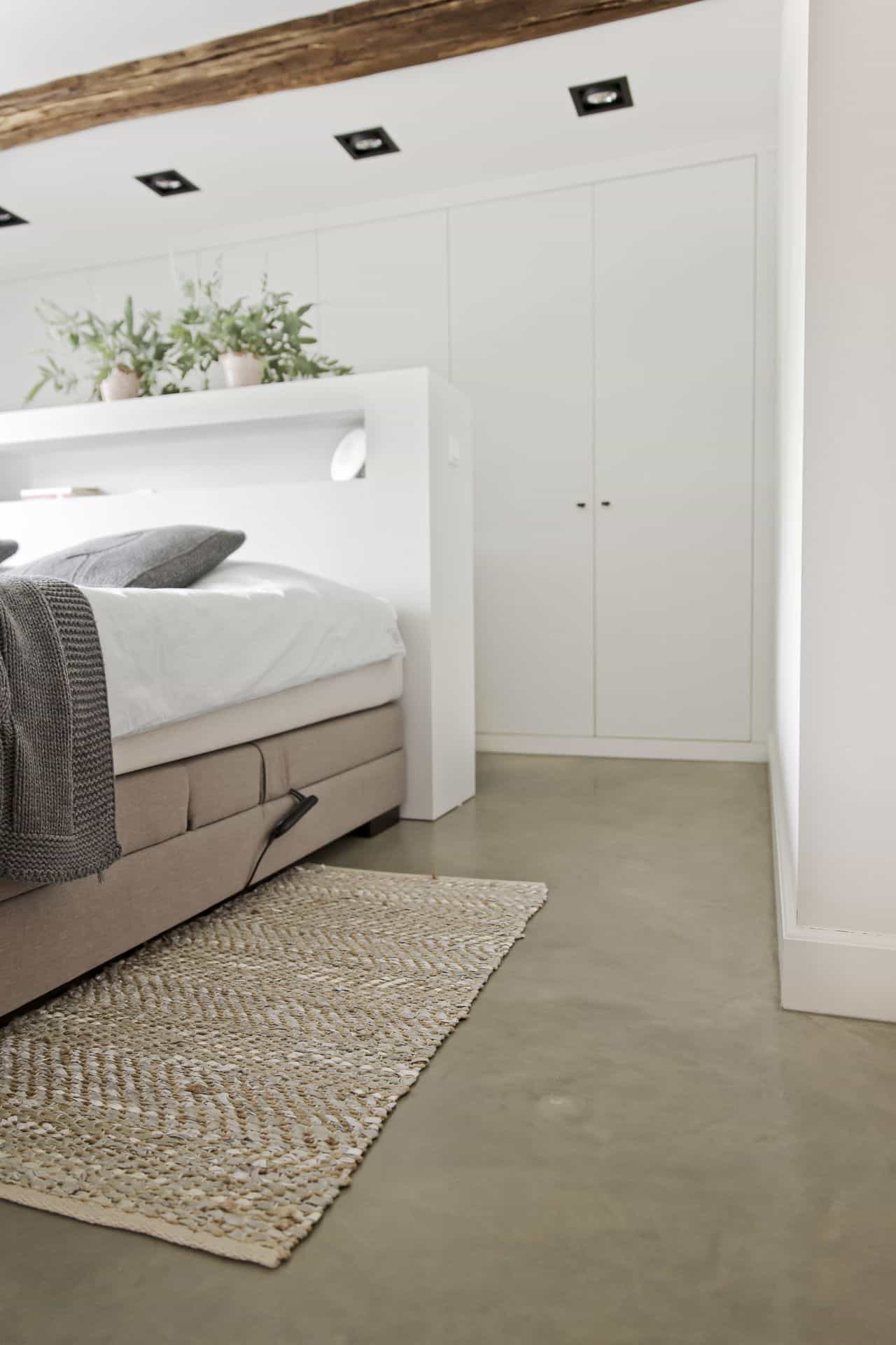 betonvloer in slaapkamer met witte muren