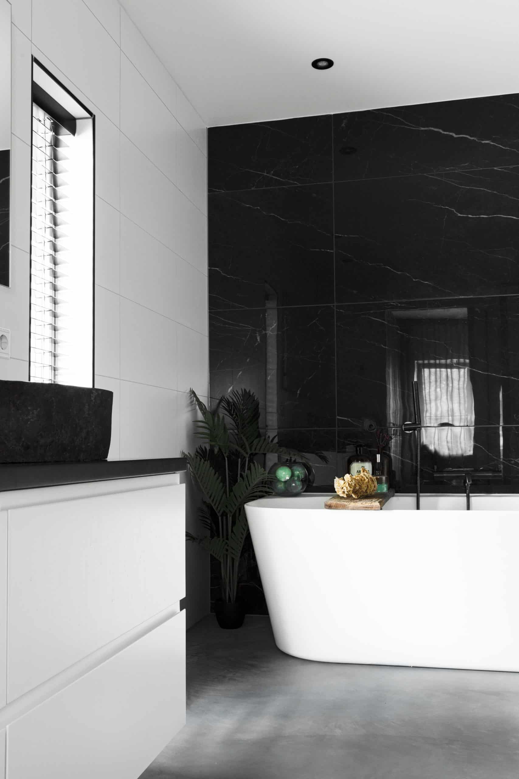 Badkamer in Hoogblokland met een gevlinderde betonvloer. Wit bad en wit badkamermeubel
