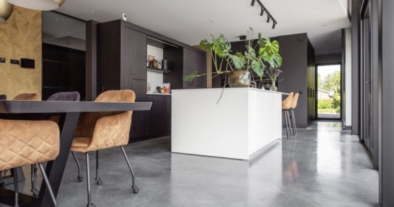 Zwarte keuken met een wit kookeiland in Nuenen, gecombineerd met een gevlinderde betonvloer.