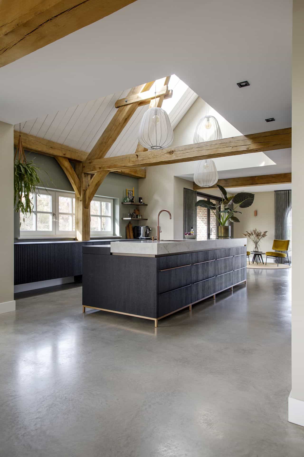 Gevlinderde woon betonvloer in Horst gecombineerd met een zwarte keuken, houten balken aan het plafond en witte en groene wanden