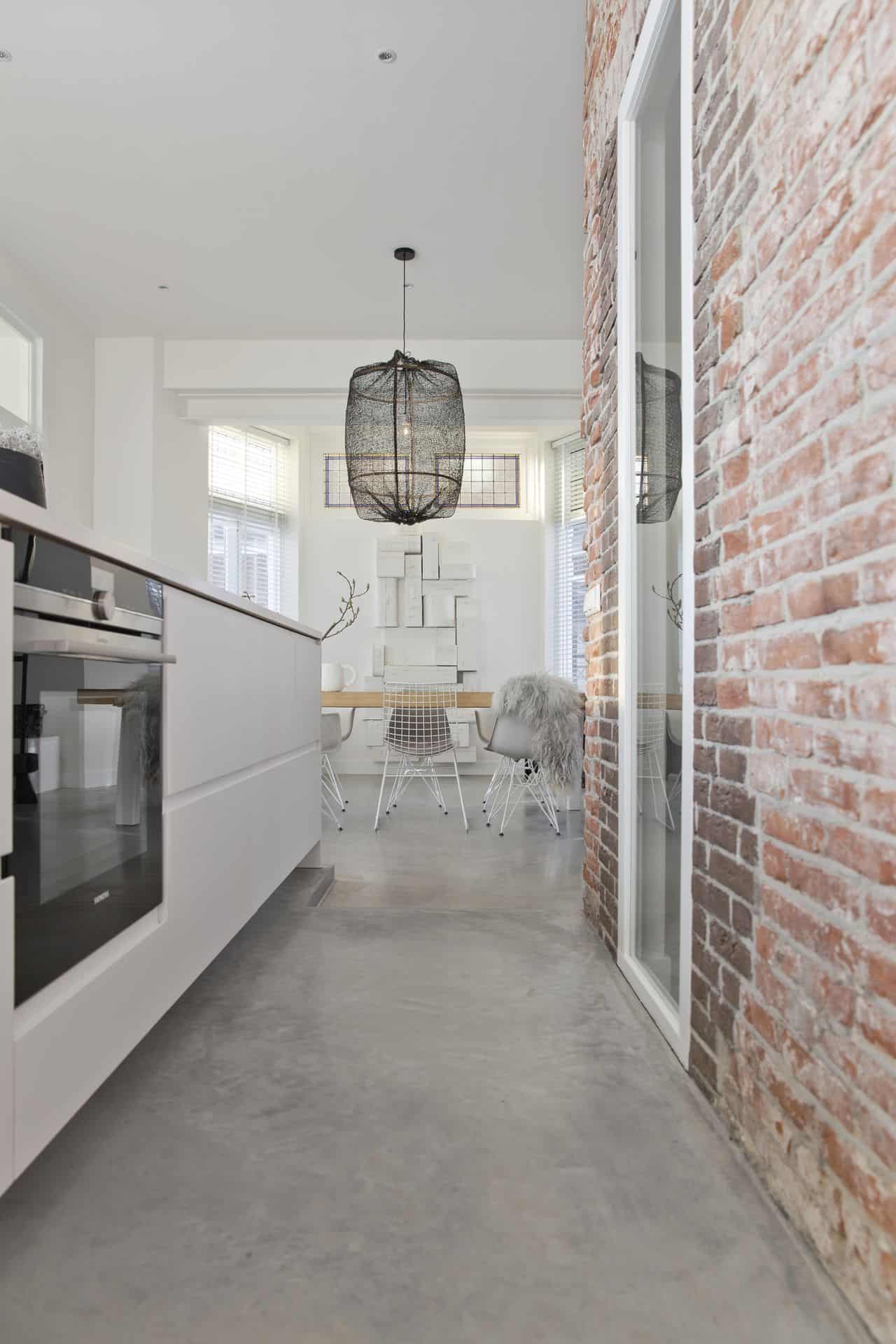 basisgrijs beton met witte keuken en stenen muur